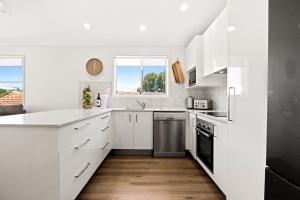 a white kitchen with white cabinets and a window at Popular Central Coastal Apartment in Maroochydore