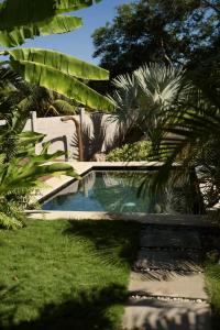 uma piscina num quintal com palmeiras em Casa MexiBali, Palapa 47 em Troncones