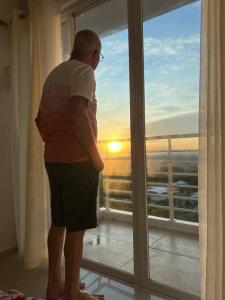 a man standing in front of a window looking at the sunset at Uptown Condo Primavera Residences in Cagayan de Oro