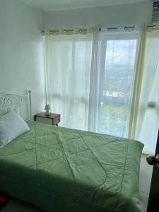 a bedroom with a green bed with a large window at Uptown Condo Primavera Residences in Cagayan de Oro