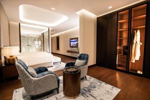 a bedroom with a bed and two chairs and a table at The Biltmore Hotel Villas Dubai in Dubai