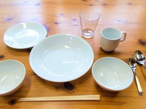 una mesa con placas blancas, palillos chinos y un vaso en Irunty Futademura en Iriomote
