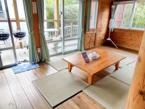 sala de estar con mesa de madera y ventanas en Irunty Futademura, en Iriomote