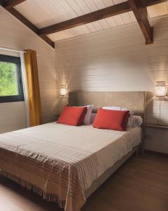 a bedroom with a bed with two red pillows at Austral House-chalet sud sauvage in Saint-Joseph
