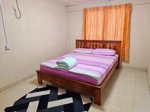 um quarto com uma cama com lençóis roxos e uma janela em Homestay D'Lempor 