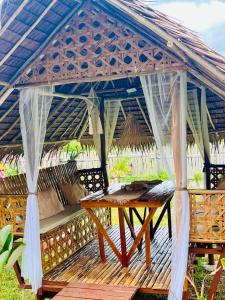 a wooden deck with a gazebo with a table at La Palapa Inn Port Barton in San Vicente