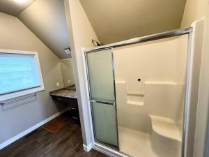 um chuveiro com uma porta de vidro na casa de banho em Harbour landing home with 2 living rooms, King bed and 2 car garage em Regina