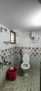 a bathroom with a toilet and a red bucket at Kingdom of dorms-the shared room in Chennai