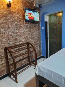 a room with a bench and a tv on a brick wall at JD Resort in Anuradhapura