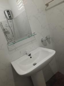 a white bathroom with a sink and a mirror at JD Resort in Anuradhapura