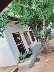 uma casa branca com dois vasos de plantas em frente em JD Resort em Anuradhapura