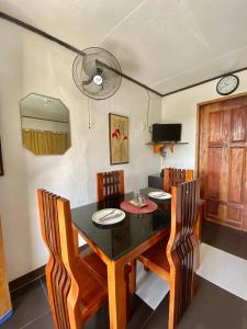 a dining room with a black table and chairs at Panagsama Holiday Cottage in Moalboal