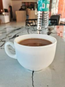 una taza de café blanca sentada en una mesa en The Kings Delight, en Jajal