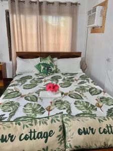 Panagsama Holiday Cottage في موالبوال: سرير مع لحاف عليه زهرة
