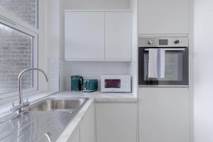 a white kitchen with a sink and a microwave at HAFH in Paddington - Double studio 2 in London