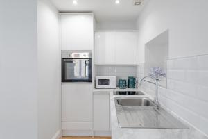 a white kitchen with a sink and a microwave at HAFH in Paddington - Double studio 3 in London