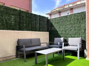 two chairs and a table on a lawn with a fence at Duplex con terraza in Renedo de Piélagos