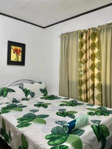 a bedroom with a bed with a green and white blanket at Panagsama Holiday Cottage in Moalboal