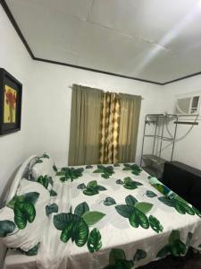 a bedroom with a bed with a green and white comforter at Panagsama Holiday Cottage in Moalboal