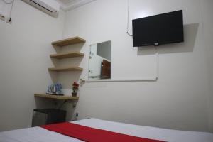 Kost K23 في سورابايا: غرفة نوم مع سرير وتلفزيون بشاشة مسطحة على الحائط