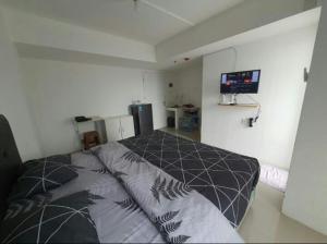 a bedroom with a bed and a flat screen tv at Urbantown Serpong in Dukuh