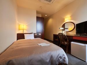 a bedroom with a bed and a desk and a mirror at Tabist Hotel New Central in Fuji