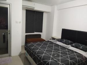a bedroom with a black bed and a window at Urbantown Serpong in Dukuh