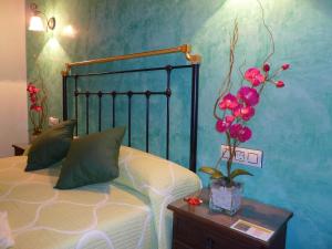 1 dormitorio con 1 cama y un jarrón de flores sobre una mesa en Casa Rural Antonio, en Vitigudino