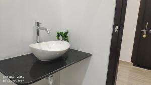 un lavabo blanco en un mostrador negro en el baño en Dhaneshwari Homestay en Varanasi