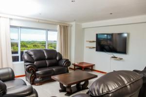 a living room with leather chairs and a flat screen tv at Santareme Seaviews in St Francis Bay