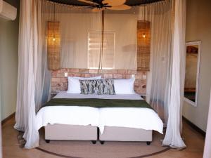 KhorixasにあるLodge Damaralandのベッドルーム(白いカーテン付きのベッド1台付)
