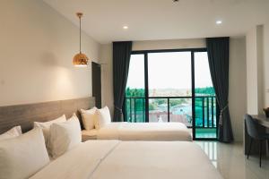 two beds in a hotel room with a balcony at Mountain&Sea Hotel Prachuap in Prachuap Khiri Khan