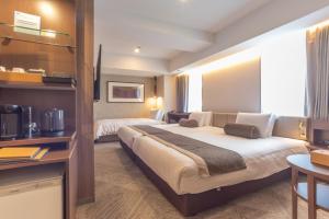 a hotel room with two beds and a desk at The Rise Osaka Kitashinchi in Osaka