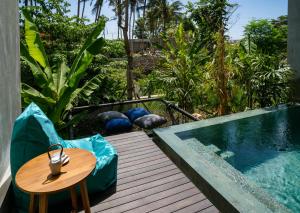 a wooden deck with a table next to a swimming pool at Langit Pitu Villas in Ketewel