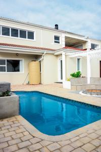 a house with a swimming pool in front of a house at Santareme Seaviews in St Francis Bay