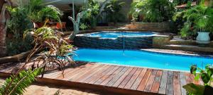 einen Pool in einem Garten mit einer Holzterrasse in der Unterkunft R A GUEST HOUSE PEMBA in Pemba
