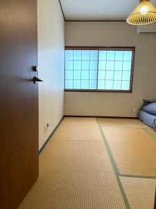 Guesthouse Hakuka في كانازاوا: غرفه فاضيه فيها باب ونافذه