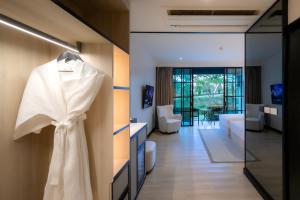 a white dress hanging on a wall in a room at Bergh Apton Khao Yai in Khao Yai
