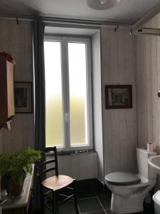 a bathroom with a toilet and a window and a chair at chambre double chez Catherine et Jean-Luc en Bretagne in Audierne