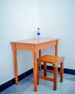 einen Tisch und einen Hocker mit einer Flasche darauf. in der Unterkunft Teranga Lodge and Restaurant in Ihumwa
