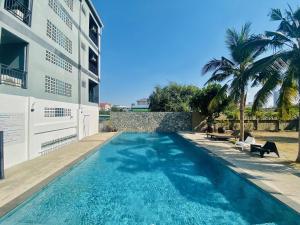 a swimming pool next to a building with palm trees at Apartment X5 in Pattaya South