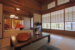 una camera con tavolo in legno e finestre di 古民家一棟貸 太田邸 a Yazu