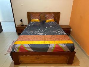 a bed in a bedroom with a wooden bed frame at Appartement Spacieux chez Keur Matou - F2 Dakar in Dakar