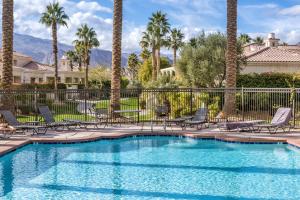 een zwembad met stoelen en palmbomen bij Desert Paradise by VARE - Puerta Azul - Pool & Spa in La Quinta