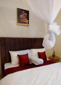 una camera da letto con un letto con lenzuola bianche e cuscini rossi di Muggiez Vacation Rentals a Kampala