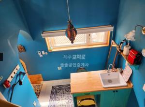 Seonjau in Jeju في جيجو: غرفة زرقاء مع حوض ونافذة
