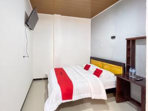 a bedroom with a bed and a tv on the wall at RedDoorz at Rose House Simpang Pemda Medan Selayan in Sunggal