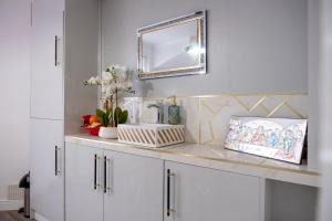 a bathroom counter with a mirror and white cabinets at Spacious Double Bedroom in Shooters Hill in London