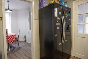 ein großer schwarzer Kühlschrank in einem Zimmer mit einem Tisch in der Unterkunft Spacious Double Bedroom in Shooters Hill in London