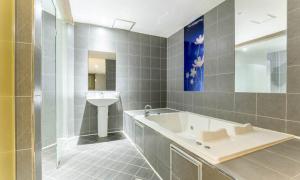 a bathroom with a bath tub and a sink at Dongtan BobosHotel in Hwaseong